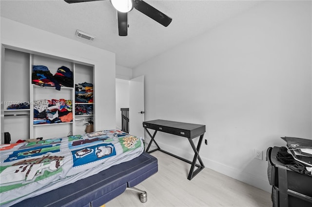 bedroom with visible vents, ceiling fan, a textured ceiling, wood finished floors, and baseboards