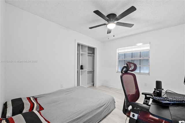 bedroom featuring ceiling fan, a textured ceiling, a closet, and wood finished floors