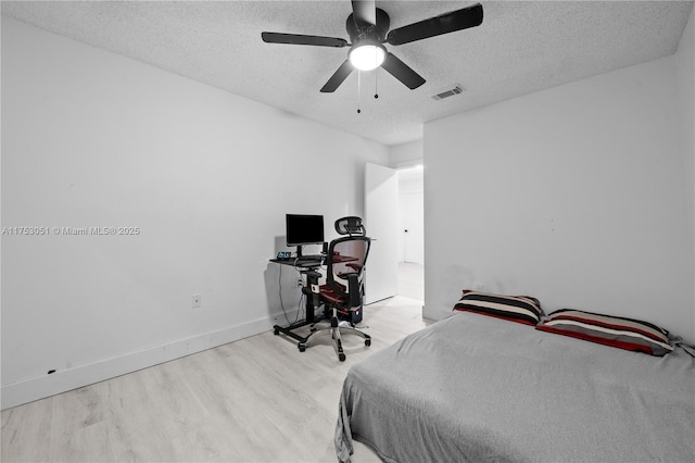 bedroom featuring baseboards, visible vents, ceiling fan, wood finished floors, and a textured ceiling