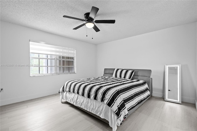 bedroom featuring ceiling fan, a textured ceiling, baseboards, and wood finished floors