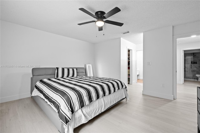 bedroom with baseboards, visible vents, a textured ceiling, and light wood finished floors