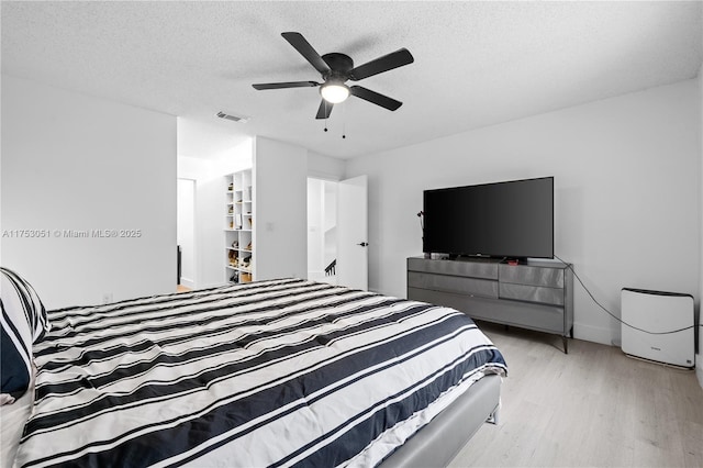 bedroom with visible vents, ceiling fan, a textured ceiling, wood finished floors, and baseboards