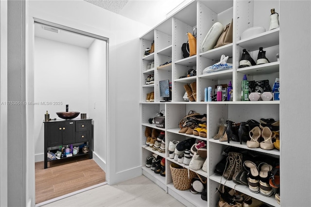 walk in closet featuring light wood-type flooring and visible vents