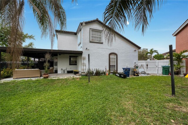 back of property featuring a patio, fence, a yard, outdoor lounge area, and stucco siding