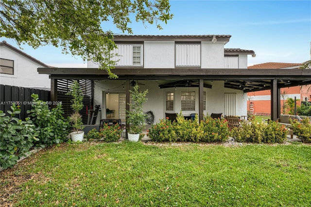 back of house featuring a yard, ceiling fan, fence, and stucco siding