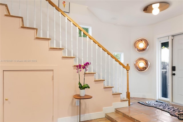 entrance foyer featuring a wealth of natural light, stairway, and baseboards