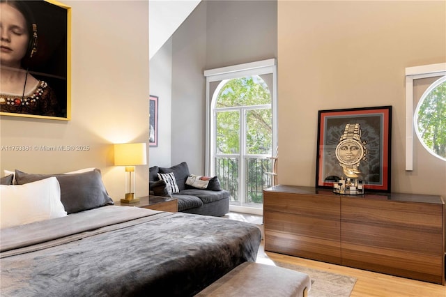 bedroom with a high ceiling and wood finished floors