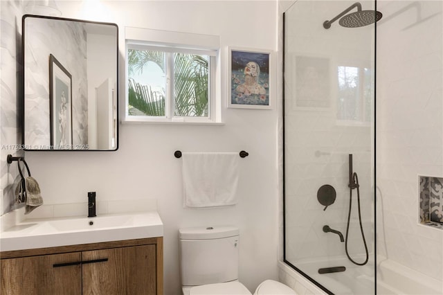 bathroom featuring tiled shower / bath, vanity, and toilet