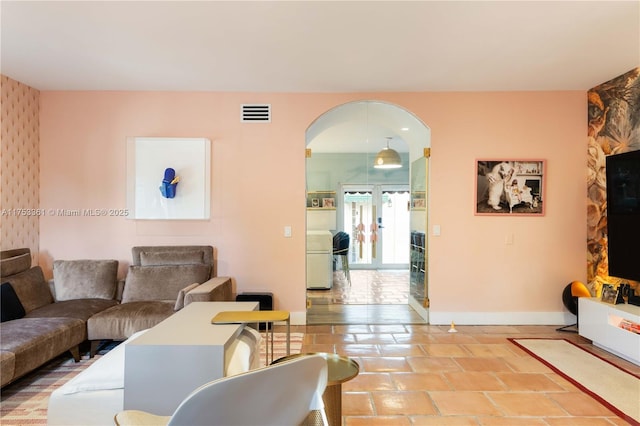 tiled living area with baseboards, visible vents, and arched walkways