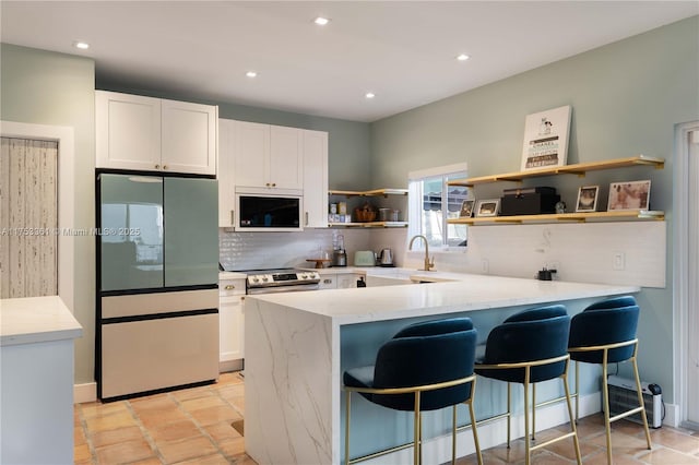 kitchen featuring appliances with stainless steel finishes, white cabinets, a sink, and open shelves