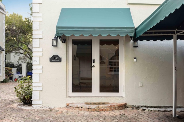 view of exterior entry featuring french doors and stucco siding