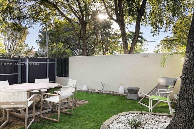 view of yard featuring fence and outdoor dining space