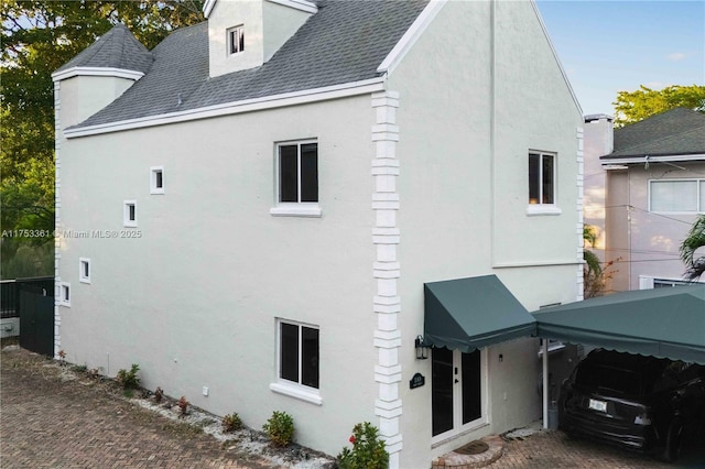 view of side of home with roof with shingles and stucco siding