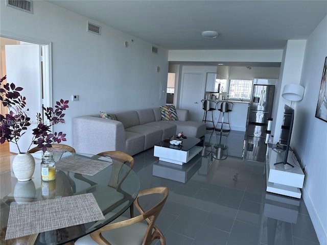 living area with visible vents, dark tile patterned floors, and baseboards