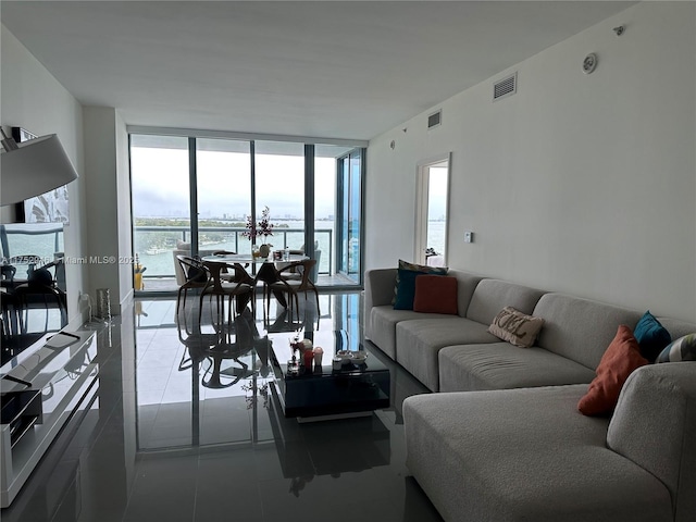 tiled living area with a water view, visible vents, and floor to ceiling windows