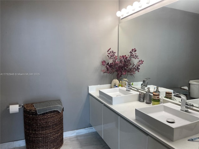 full bath featuring double vanity, a sink, and toilet