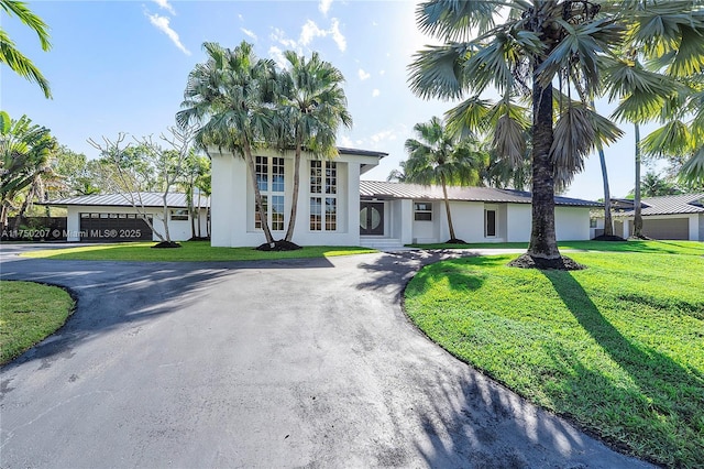 view of front of property with driveway, metal roof, a front lawn, and stucco siding