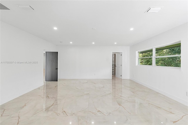 spare room with marble finish floor, baseboards, visible vents, and recessed lighting