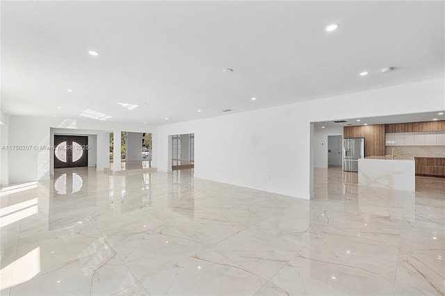 unfurnished living room featuring marble finish floor, a sink, and recessed lighting