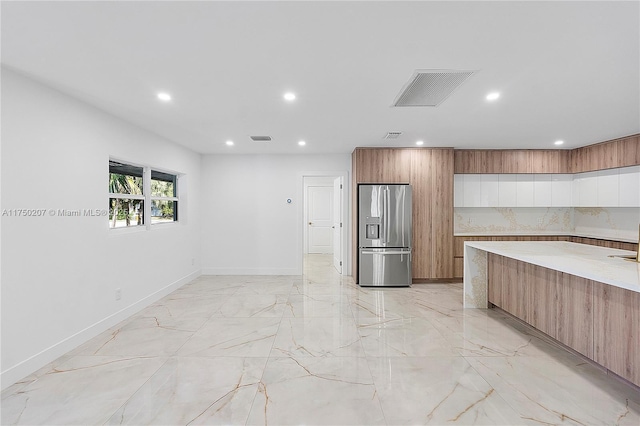 kitchen featuring marble finish floor, light countertops, visible vents, modern cabinets, and stainless steel fridge