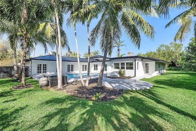 back of property featuring a yard, a standing seam roof, a patio area, metal roof, and an outdoor pool