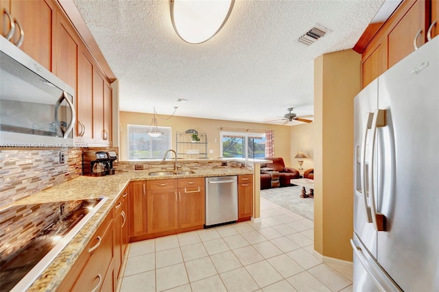 kitchen with a peninsula, a sink, visible vents, appliances with stainless steel finishes, and brown cabinets