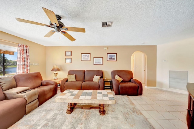 living area with arched walkways, light tile patterned floors, a textured ceiling, and visible vents