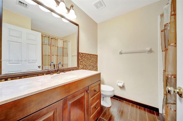 bathroom featuring toilet, visible vents, wood finished floors, and vanity