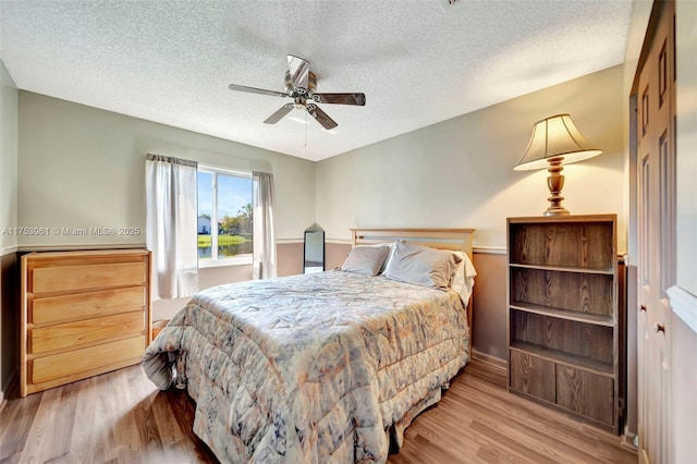 bedroom featuring a textured ceiling, a ceiling fan, and wood finished floors