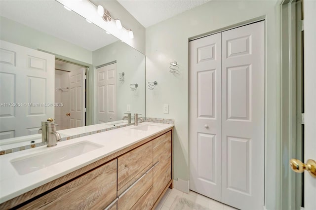 bathroom featuring a closet, a sink, and double vanity