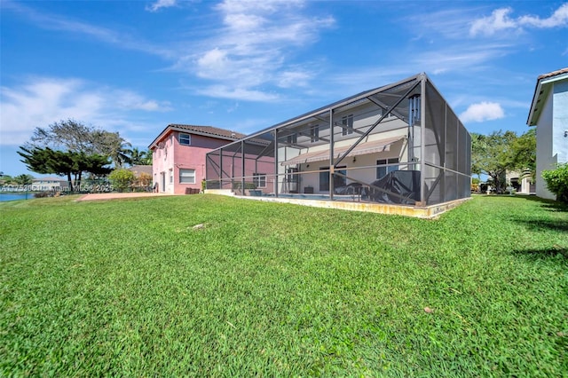 rear view of property featuring a tile roof, glass enclosure, a yard, and stucco siding