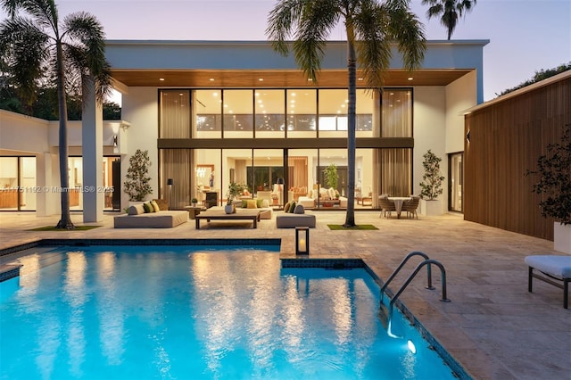 back of house with a patio area, an outdoor pool, and stucco siding