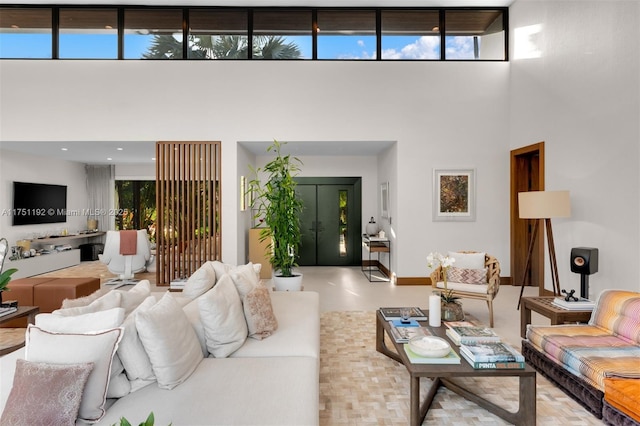 living room featuring a towering ceiling, plenty of natural light, and baseboards