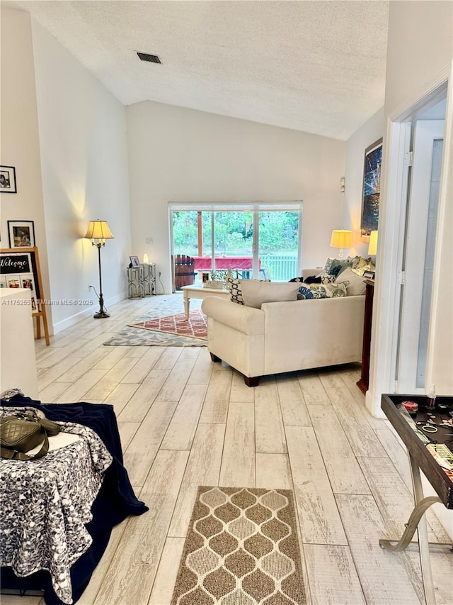 living area featuring baseboards, a textured ceiling, visible vents, and wood finished floors