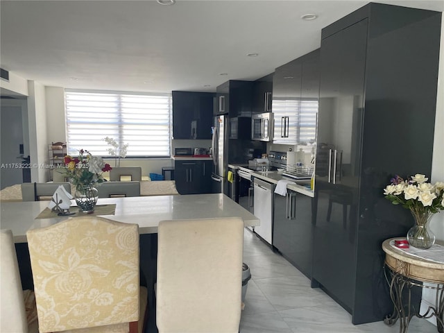 kitchen featuring a breakfast bar, appliances with stainless steel finishes, light countertops, and dark cabinetry