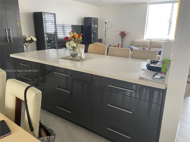 kitchen featuring marble finish floor, modern cabinets, light countertops, and dark cabinets