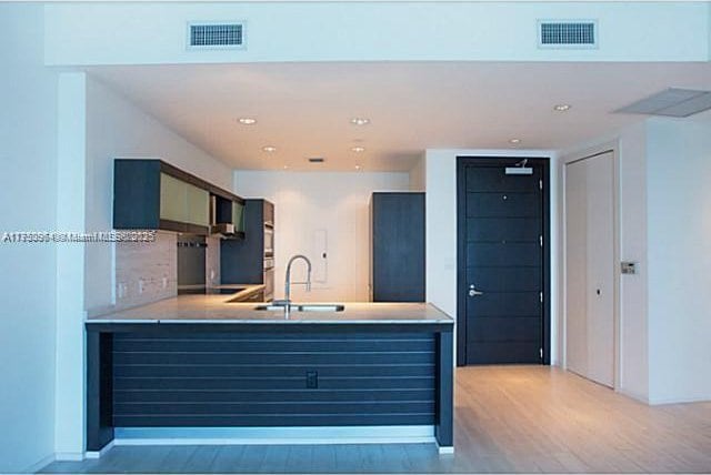 kitchen featuring light wood-style floors, light countertops, visible vents, and a sink