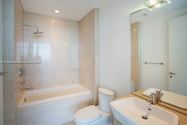 bathroom with tiled shower / bath combo, vanity, and toilet