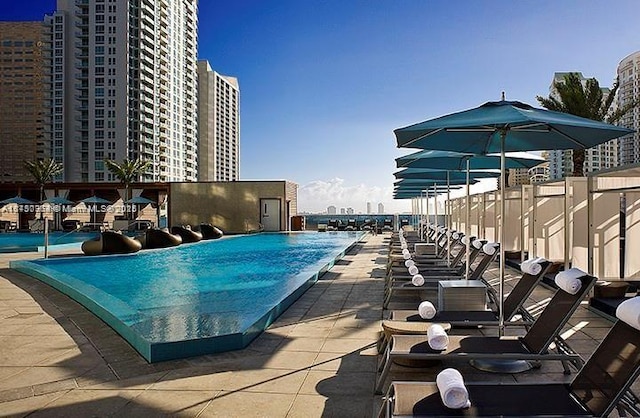 community pool featuring a patio area, fence, and a city view