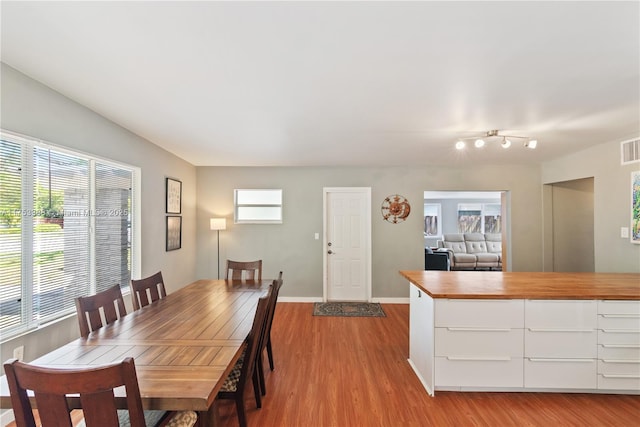 dining space with baseboards, light wood-style flooring, and visible vents