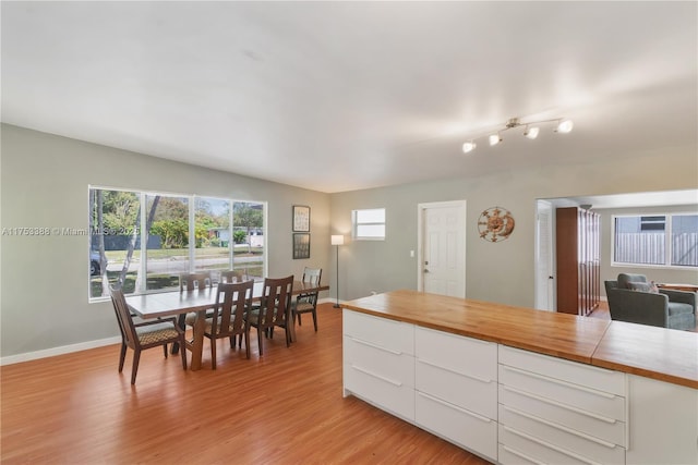 kitchen featuring light wood-type flooring, light countertops, white cabinetry, and baseboards