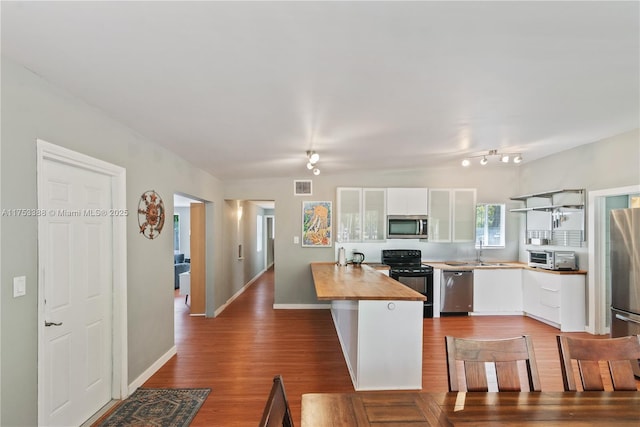 kitchen featuring white cabinetry, a sink, glass insert cabinets, stainless steel appliances, and butcher block countertops