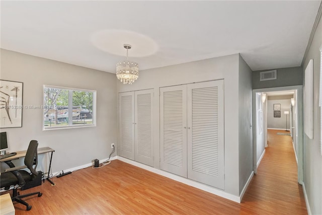 office area featuring visible vents, light wood finished floors, baseboards, and a notable chandelier