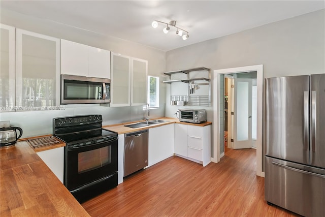 kitchen featuring wooden counters, white cabinets, a sink, light wood-style flooring, and stainless steel appliances
