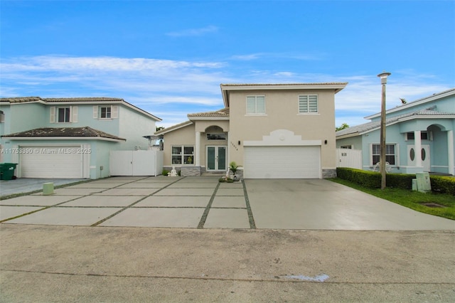 view of front of house featuring french doors, a tile roof, stucco siding, concrete driveway, and an attached garage