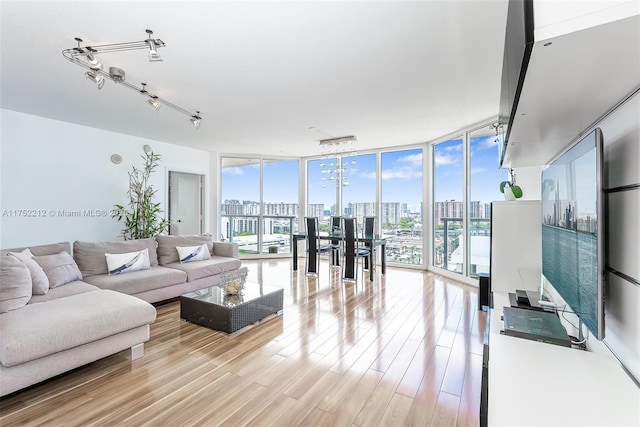 living room featuring light wood-type flooring, a wall of windows, and track lighting