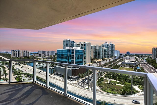 balcony at dusk with a city view and a water view