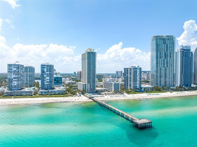 drone / aerial view with a water view, a view of city, and a beach view