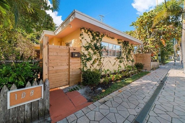 view of side of home featuring fence and stucco siding