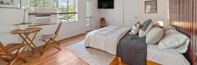 bedroom with light wood finished floors, cooling unit, and baseboards